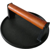 Firsgrill cast iron grill press with wood handle resting on grill for even sear