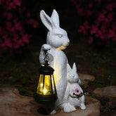 LXOUMEI solar bunny statue with lantern lights your garden at dusk.