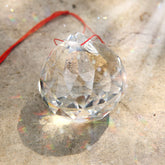 MerryNine 60mm clear crystal ball prism catching sun to cast vivid rainbows.