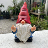 Middle Finger Gnome statue in garden with hand-painted details, funny outdoor décor.