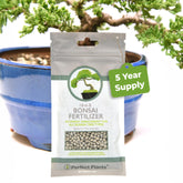 Perfect Plants bonsai fertilizer pellets in a jar support healthy growth and rich soil.