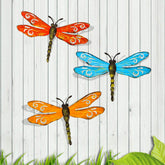Scwhousi metal dragonfly wall decor on a fence with rustic gold accents.