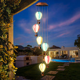Singingarden hot air balloon wind chime on fence adds colorful daytime charm and evening glow.