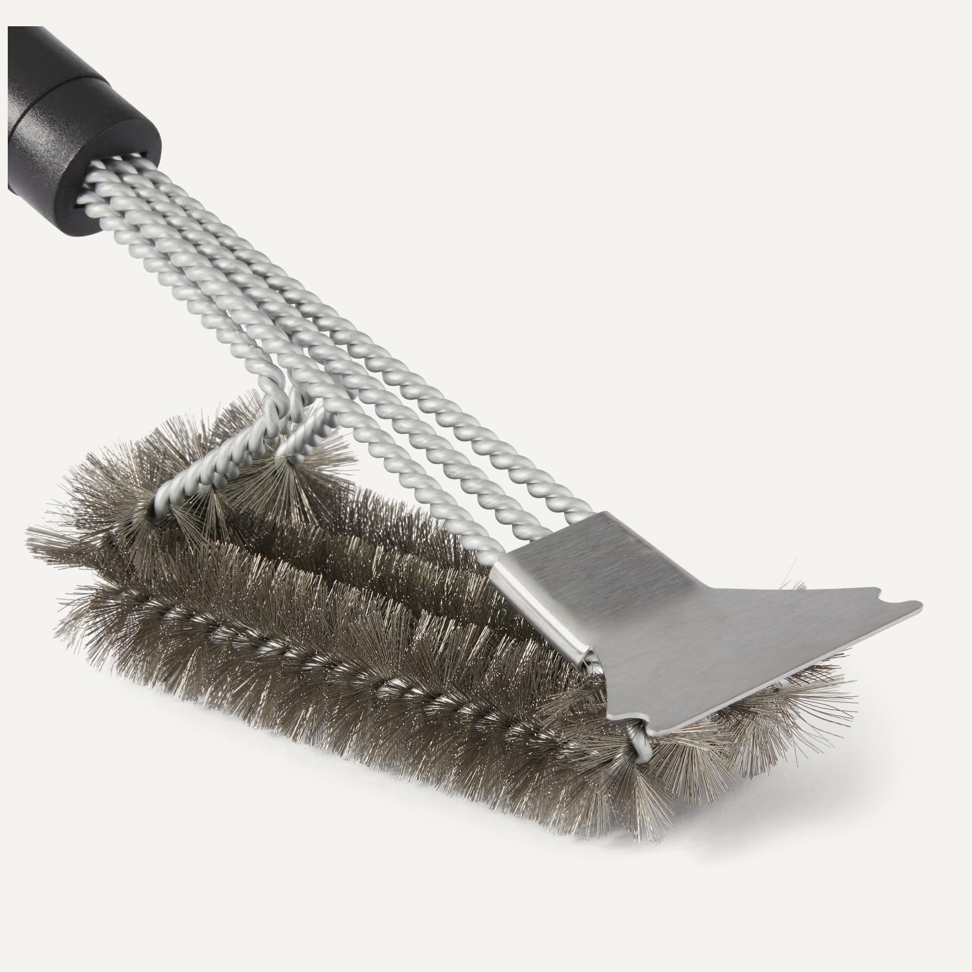 Amazon Basics grill brush closeup shows bristles and scraper ready to tackle grime.