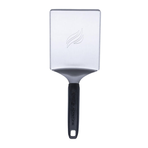 Blackstone hamburger spatula handle view showing ergonomic, cool-grip control on a hot griddle.
