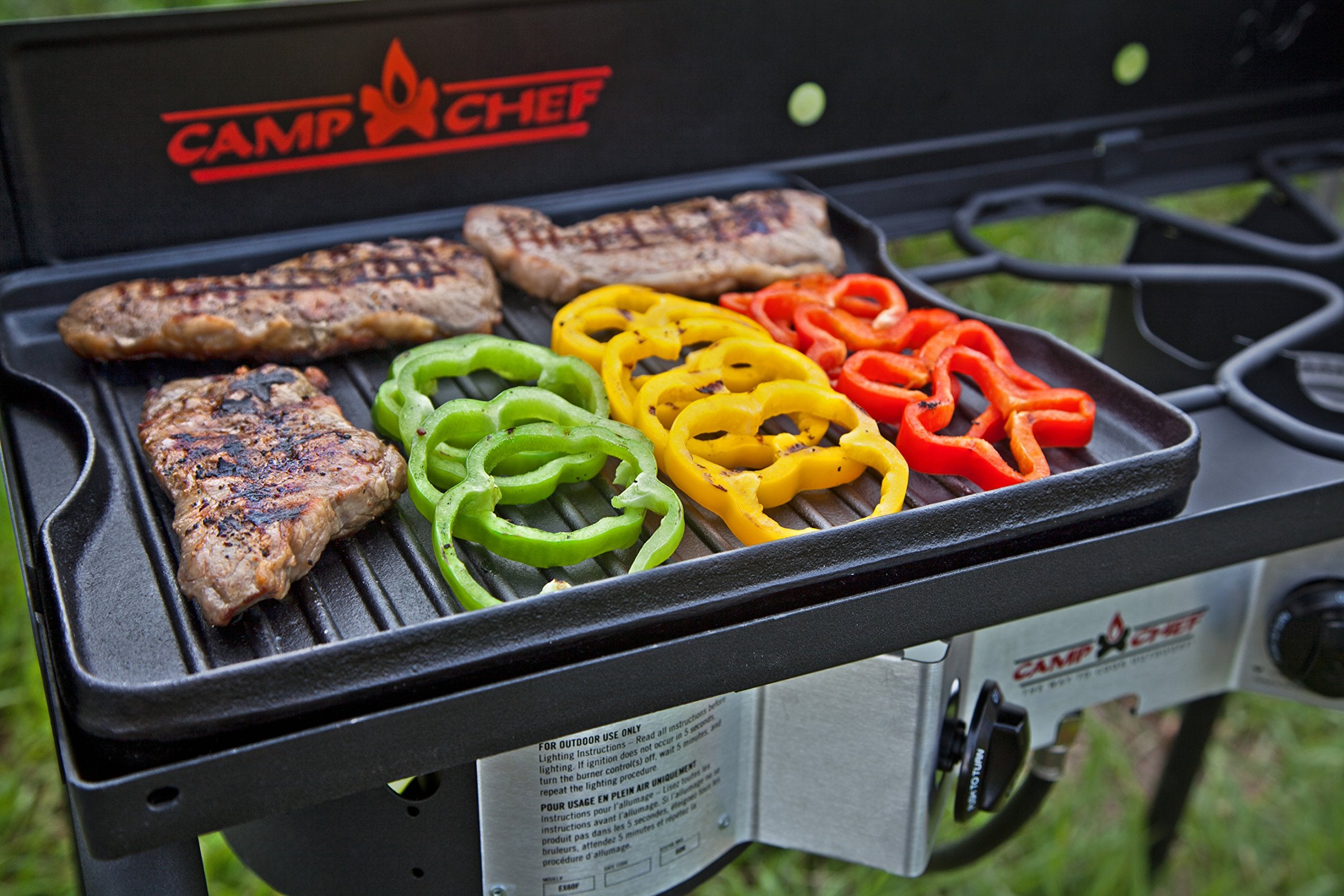 Camp Chef griddle sizzling bacon and eggs on a portable setup