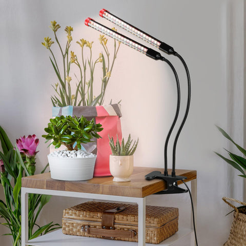FECiDA 2026 two-head grow light illuminating small indoor plants on a desk.
