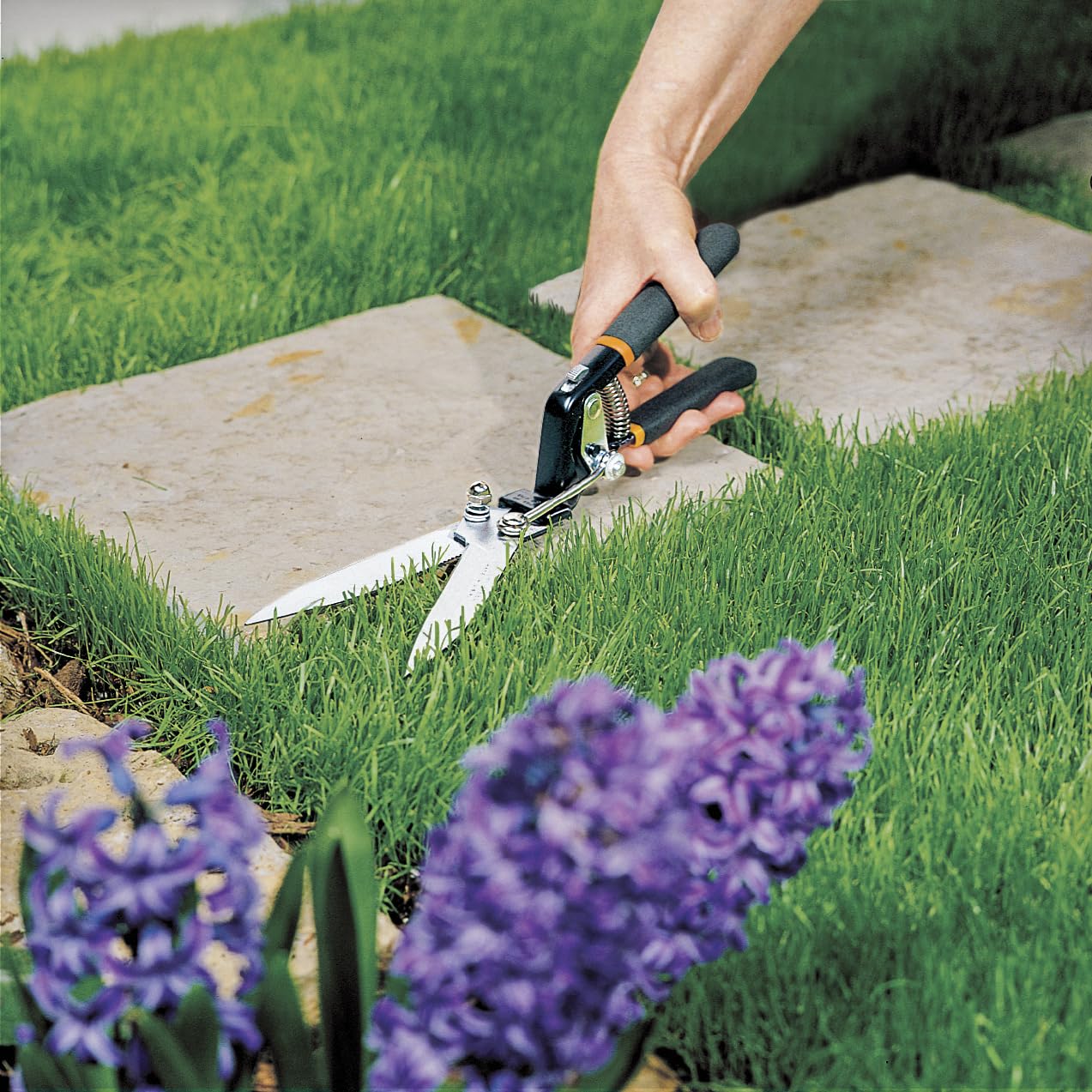 Fiskars grass shears serrated blade cutting action demonstrates durable performance.