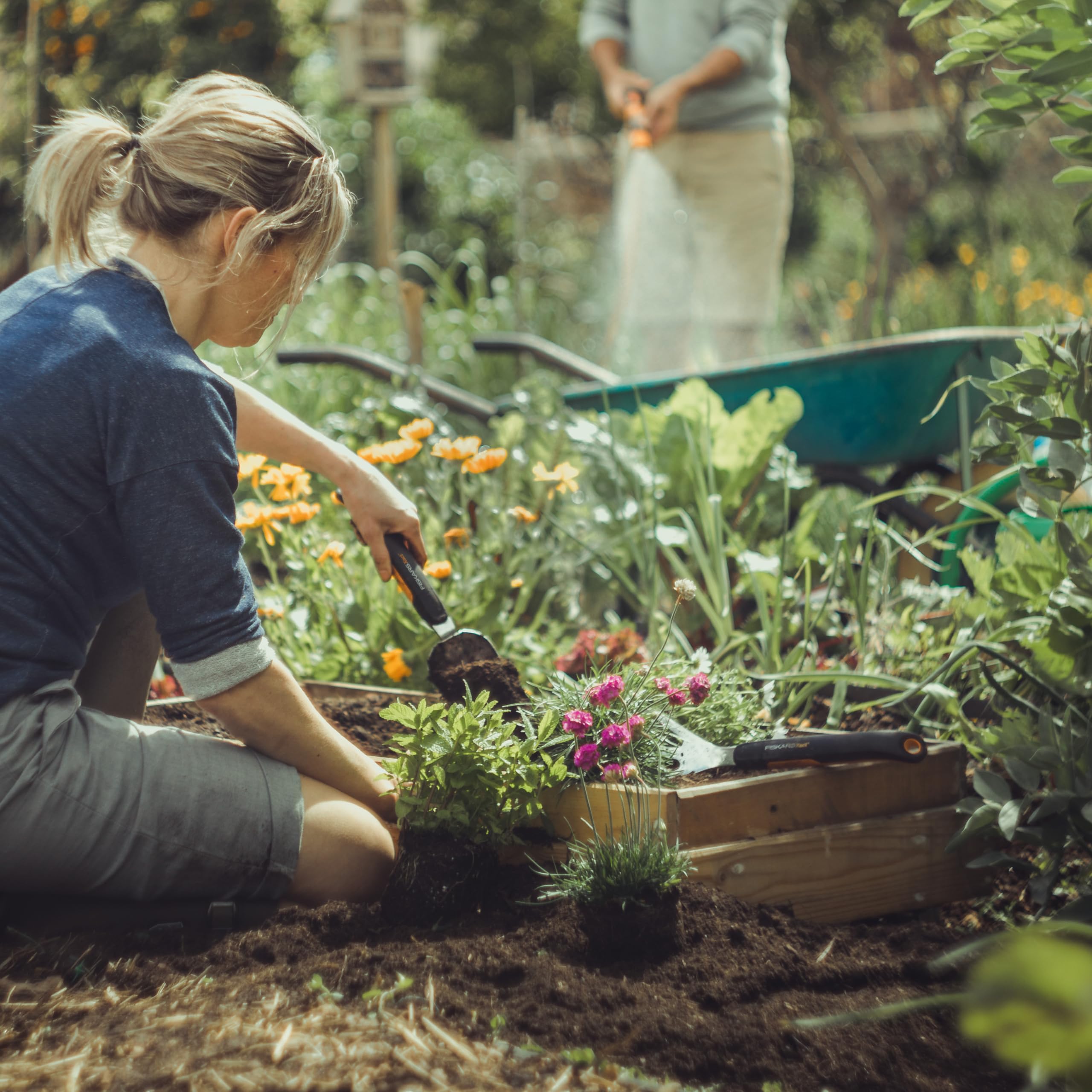 Fiskars Xact cultivator used for weed removal in a flower bed