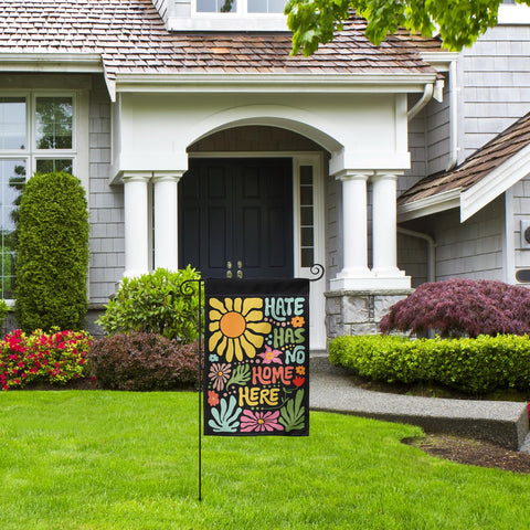 Generic Hate Has No Home Here flag enhances garden visibility in a flower bed