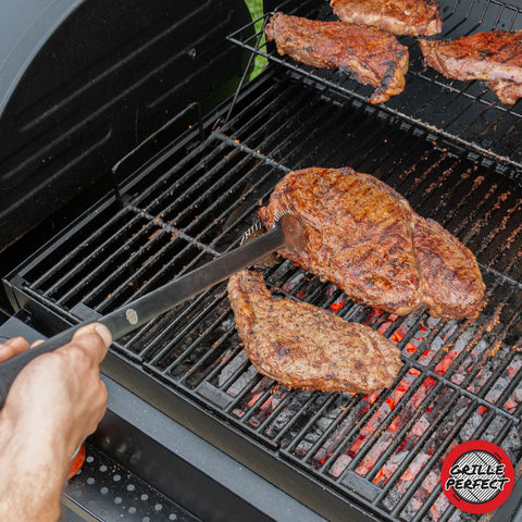 Grille Perfect tongs in use with large meats, bread, and vegetables