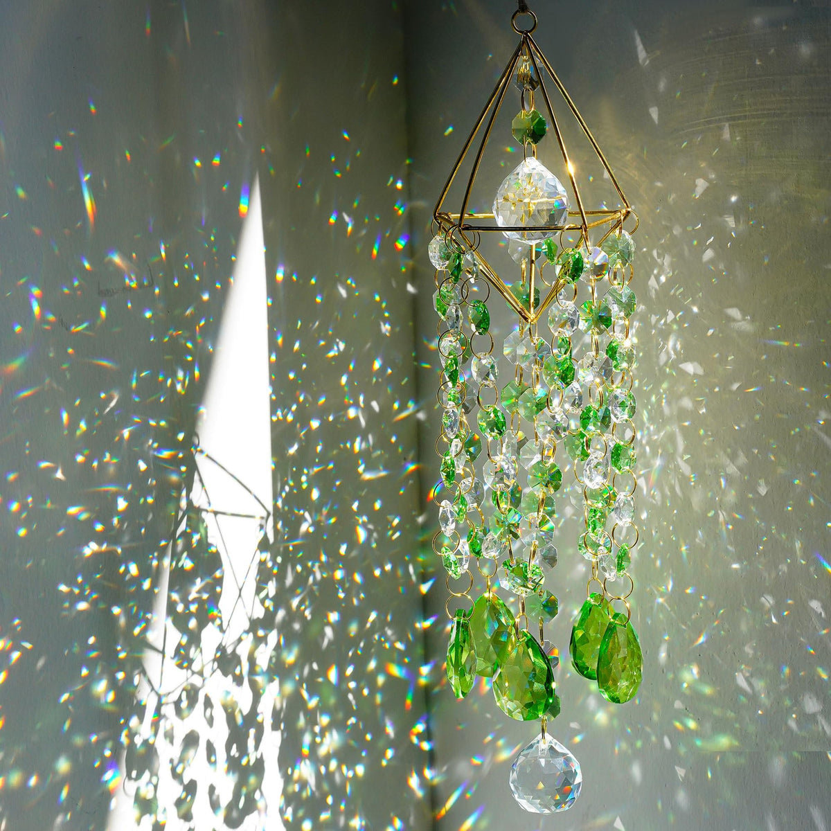 HDCRYSTALGIFTS green crystal suncatcher glows with rainbow light in a window