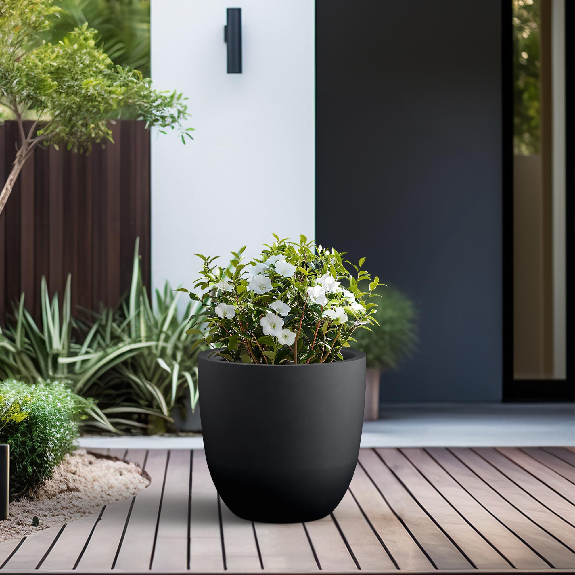 Kante 18-inch round concrete planter placed indoors with lush greenery.