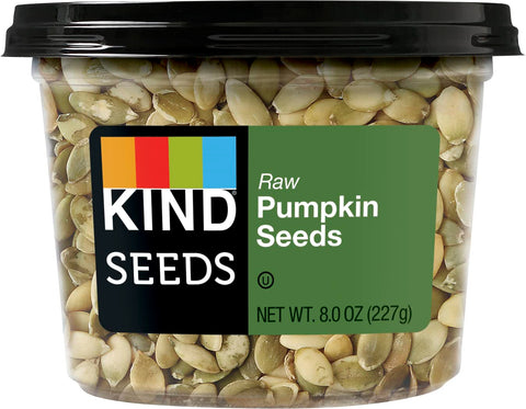 KIND Raw Pumpkin Seeds pouring to top salads for crunch and nutrition.