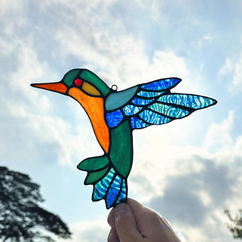 Lcensp hummingbird suncatcher on glass door catches daylight.