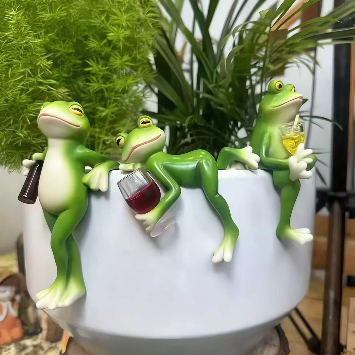 Lgkxn Tipsy Frog figurine set sits on a pot, adding whimsy to outdoor decor.