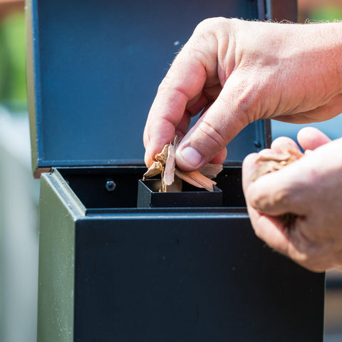 Masterbuilt slow smoker with wood-chip feed system delivering up to six hours of smoke.