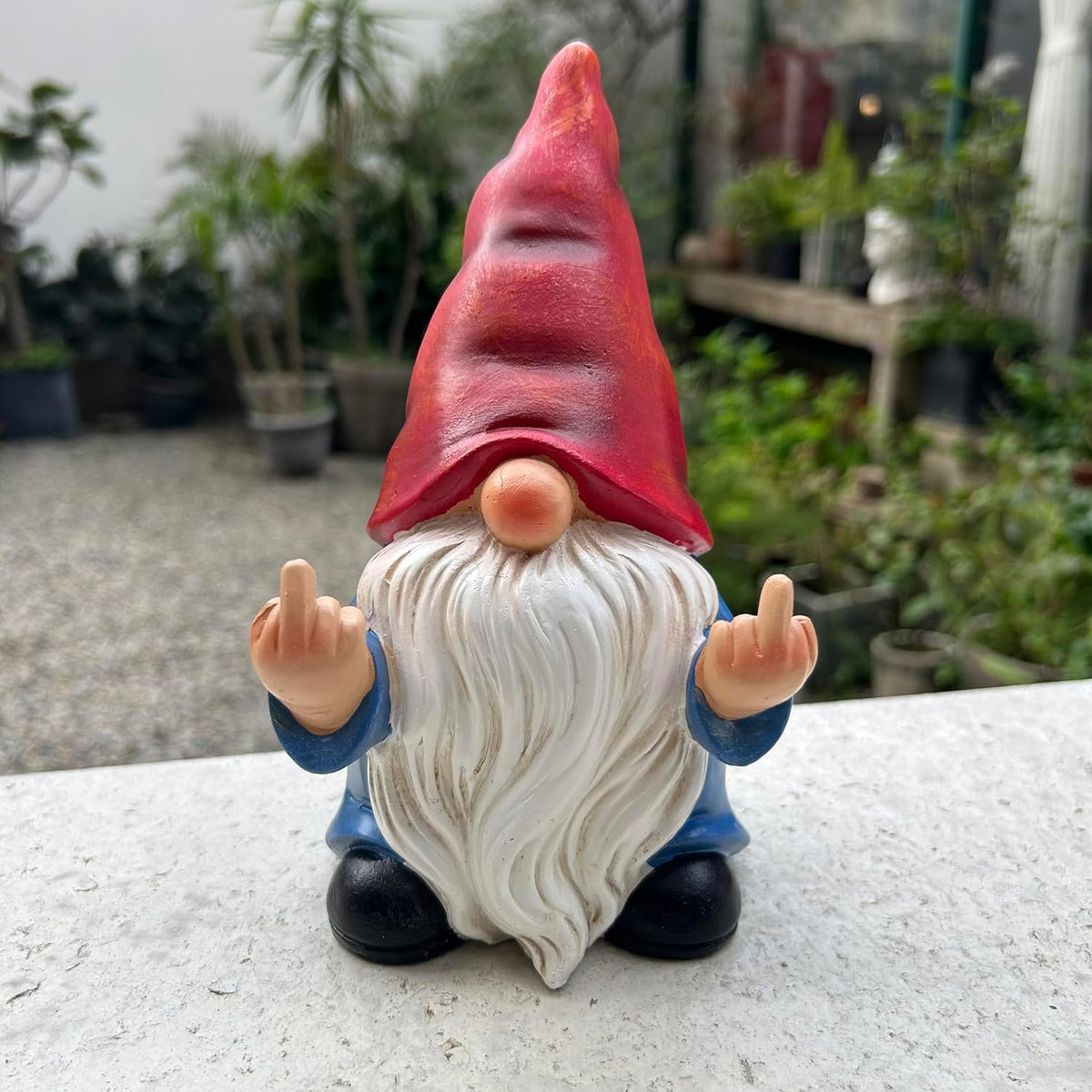 Middle Finger Gnome statue in garden with hand-painted details, funny outdoor décor.