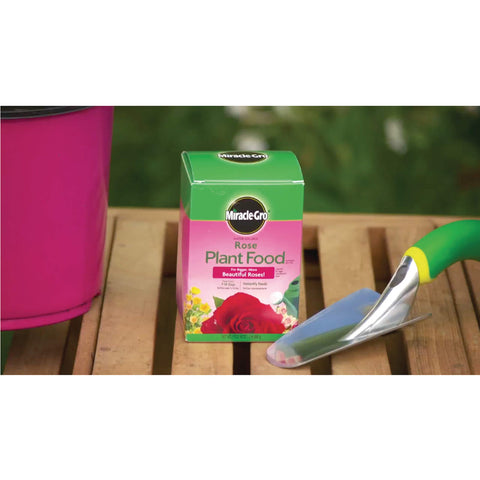 Miracle-Gro Garden Feeder applying fertilizer to soil near roses.