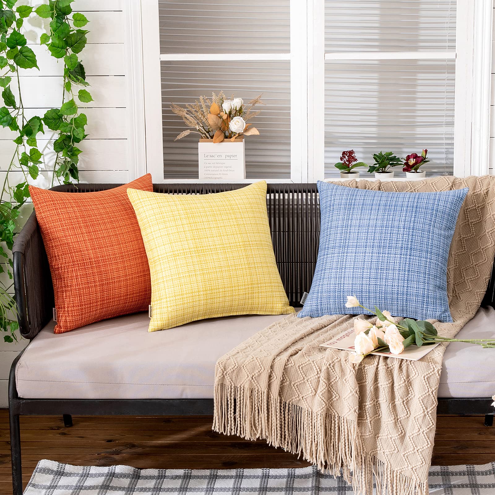 MIULEE yellow pillow cover in a garden setting focusing on weather-friendly fabric.