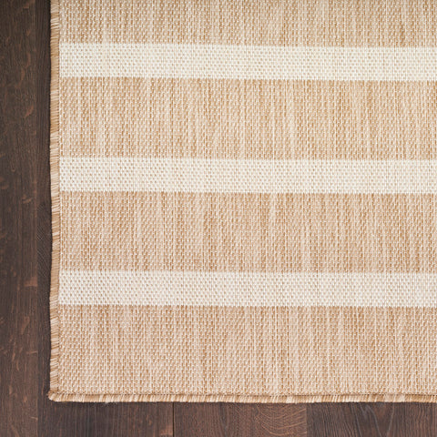 Nourison Positano beige ivory outdoor rug rolled out on a deck.