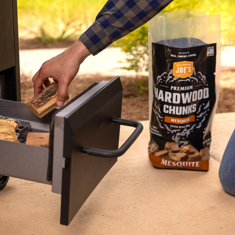 Oklahoma Joe's Mesquite Wood Chunks on coals for strong smoke flavor.