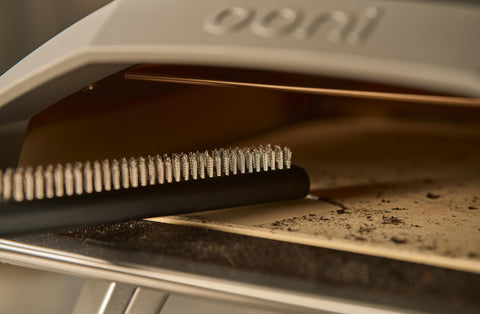 Ooni stone-cleaning action removes ash and residue from pizza stone surface.