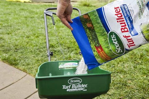 Dry lawn ready for early spring application with product spreader nearby.