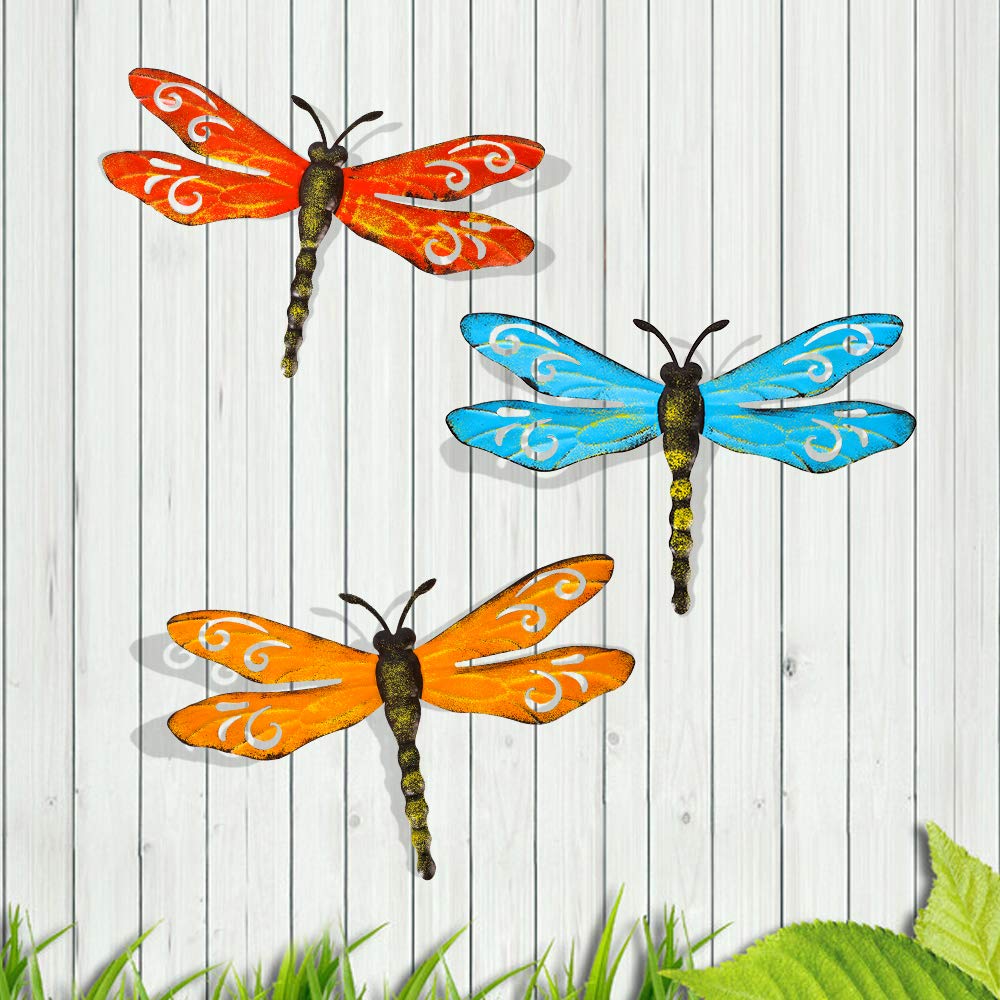 Scwhousi metal dragonfly wall decor on a fence with rustic gold accents.
