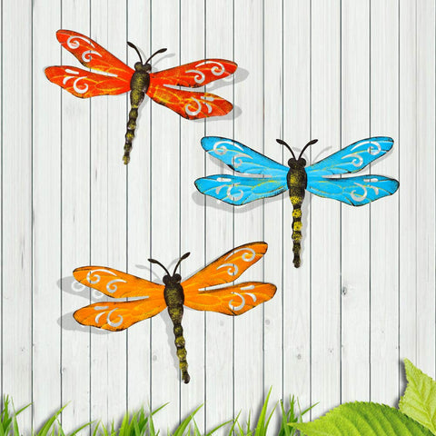 Scwhousi metal dragonfly wall decor on a fence with rustic gold accents.