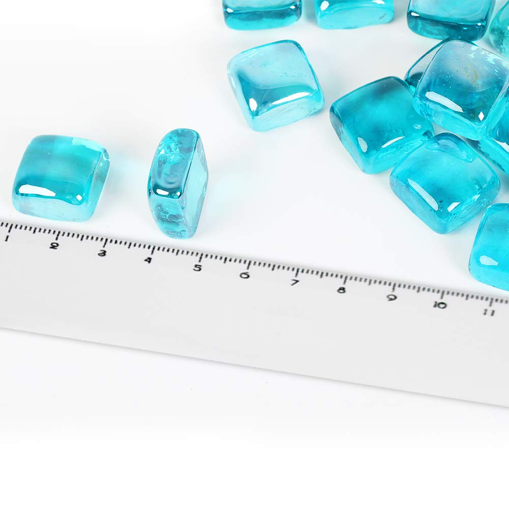 Caribbean Blue reflective fire glass cubes illuminate a fire pit with ambient glow.