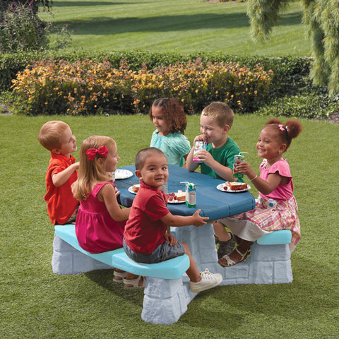 Step2 Sun & Fun Picnic Table shown indoors and outdoors for versatility.