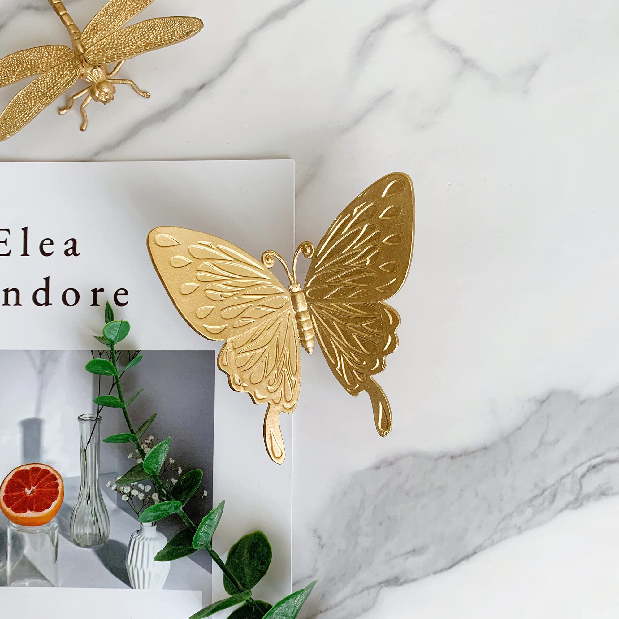 Tricune gold butterfly sculpture closeup reveals intricate metalwork and gold finish.