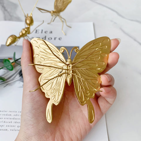 Tricune gold butterfly sculpture in garden corner, weatherproof finish adds charm.