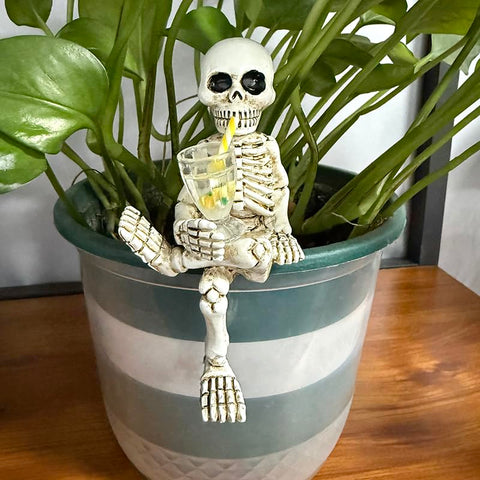 WACSLDN skeleton on a flowerpot in a garden setting, weatherproof for seasonal display.