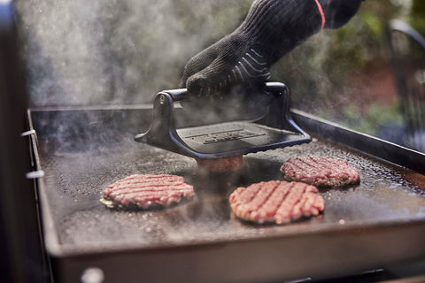 Weber Griddle Press handling four slices of bacon at once for efficiency.