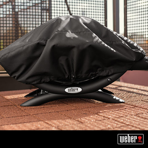Weber Premium Bonnet Cover Q1000/100 in black close-up shows waterproof, UV-resistant fabric
