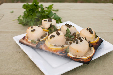 Wildwood Grilling salmon on cedar plank for flavorful, moist cooking.