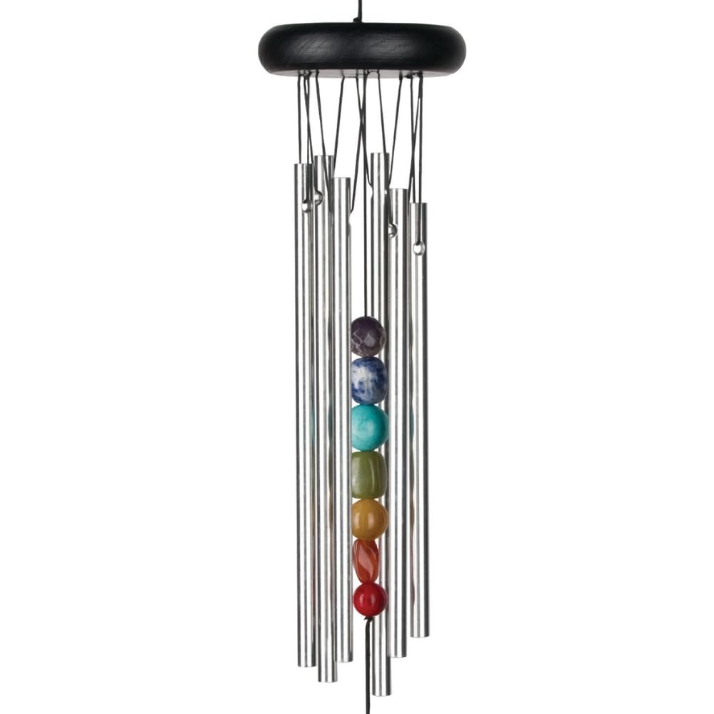 Woodstock Chimes Chakra Seven Stones chime hanging on a porch with tranquil backyard ambiance