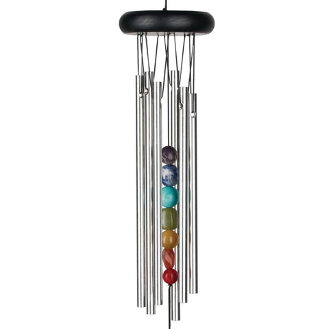 Woodstock Chimes Chakra Seven Stones chime hanging on a porch with tranquil backyard ambiance