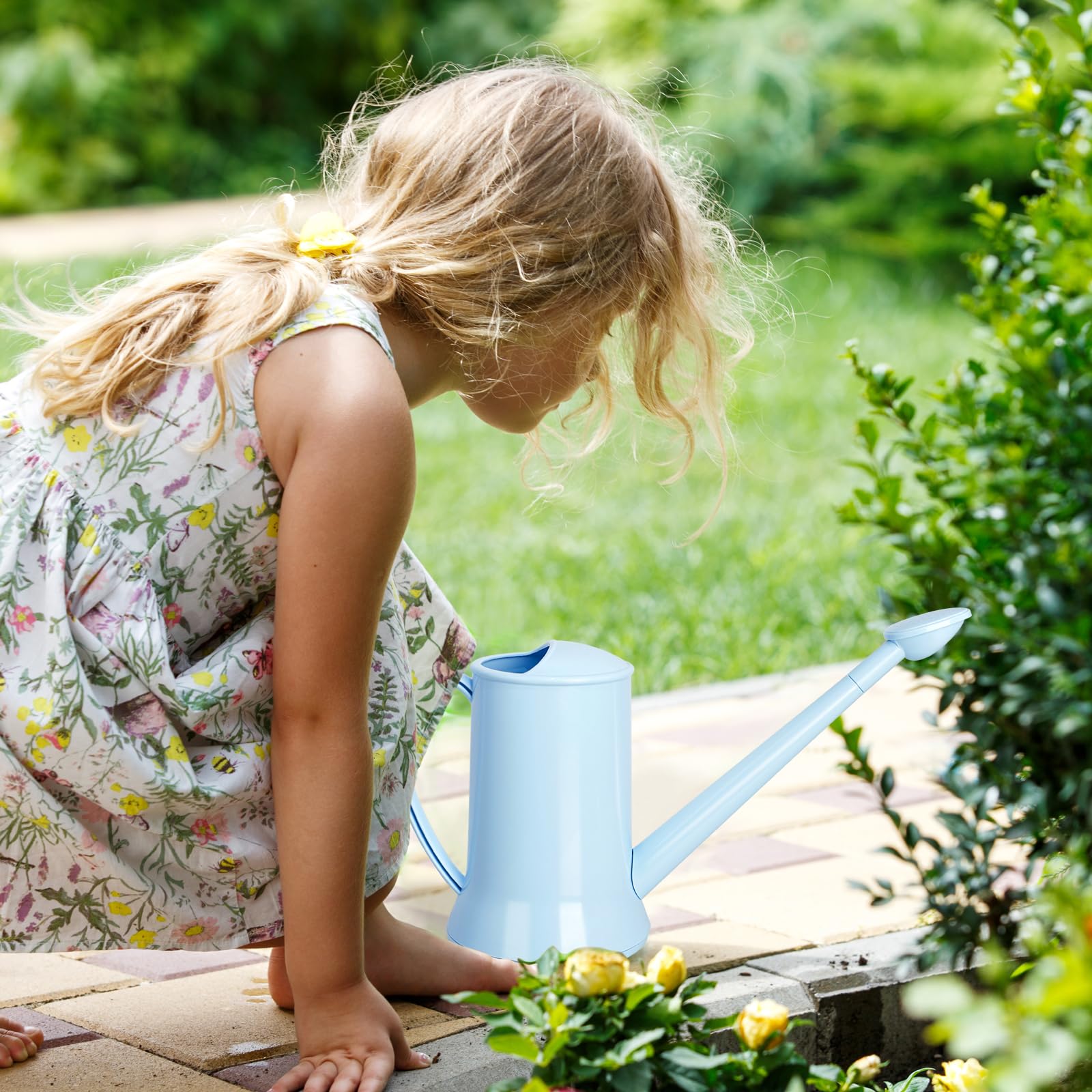 XXXFLOWER blue watering can resting on a windowsill with greenery