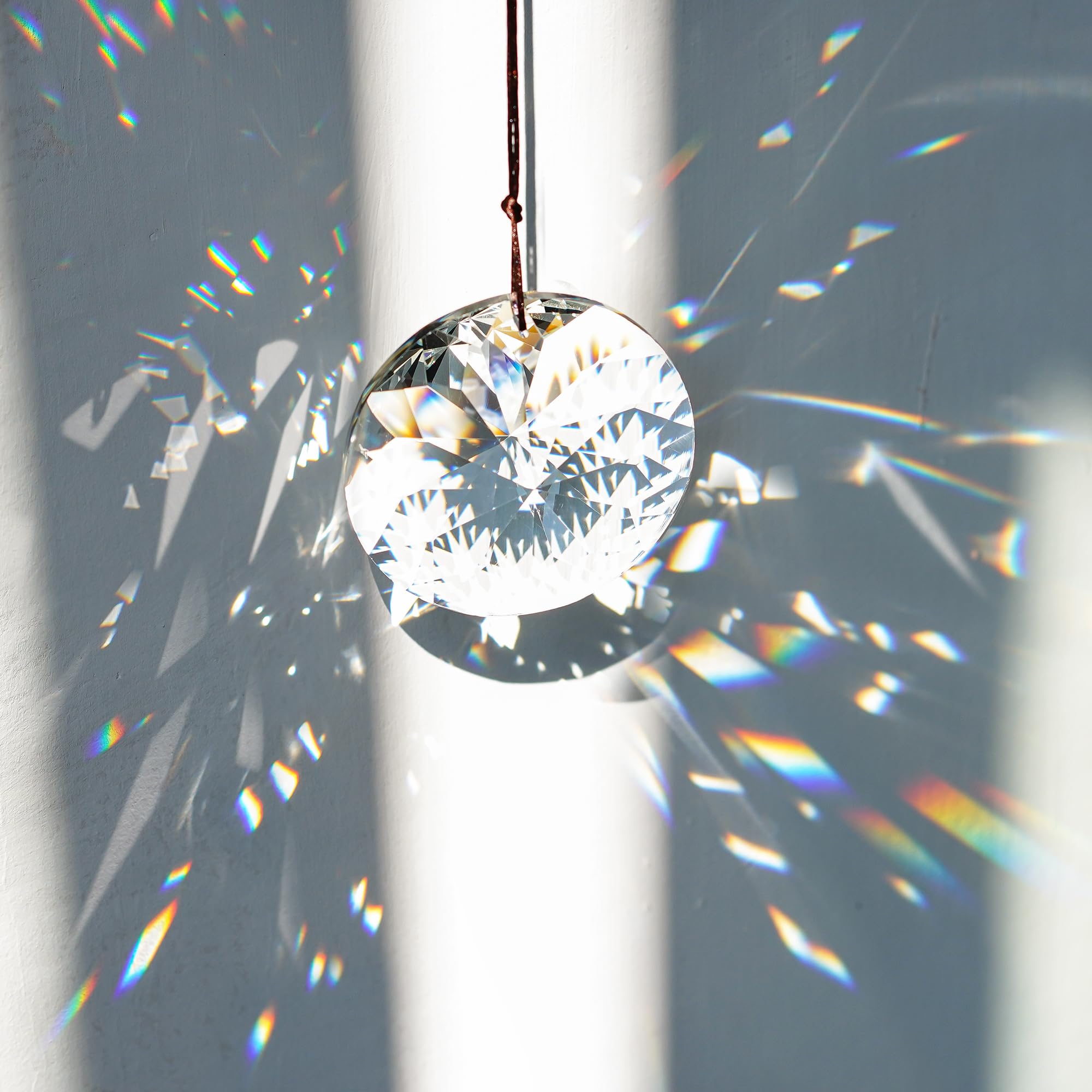YU FENG Bauhinia convex crystal prism hangs from a window for light play.