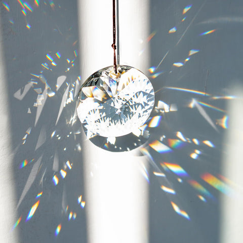 YU FENG Bauhinia convex crystal prism hangs from a window for light play.